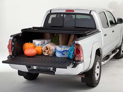 Groceries and other shopping items displayed in the back of a pickup truck with a bed liner